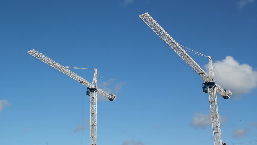 Two cranes.  White tower cranes against blue sky. Realtime shot. Construction in Toronto. 