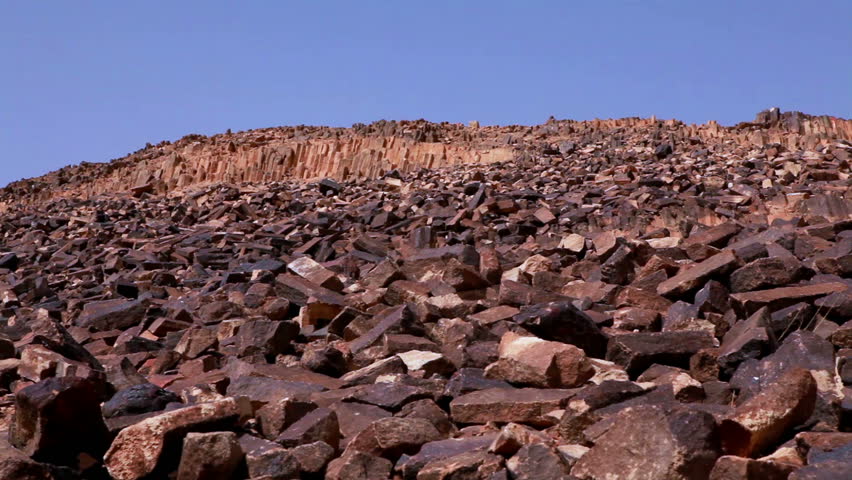 Low angled slide dolly move left to right of the rocky hillside of Ha-Minsara (The Carpentry Shop), a geological formation in the Mitzpe Ramon Crater in Israel. 