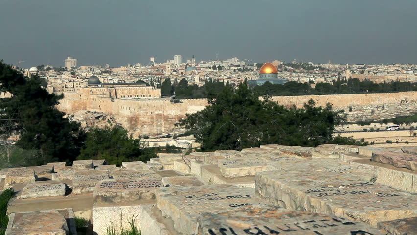 Slider dolly across the  graves at the Jewish cemetery of Jerusalem, Israel with the east wall of the Old City and the Temple Mount with the Dome Of The Rock and Al-Aqsa Mosque in the background.