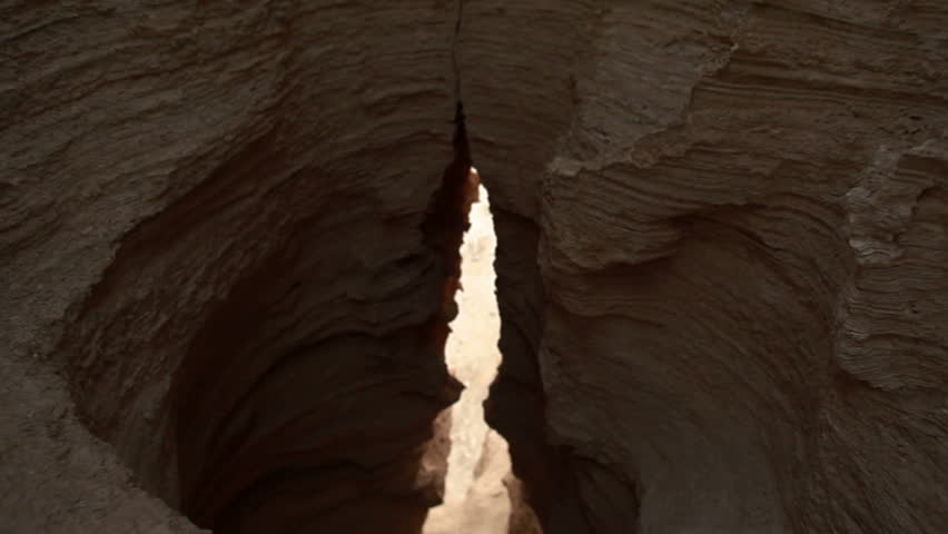 Ascending slider dolly move up and out of the birth canal of the earth.  The tunnel is in the Ein Gedi desert around the foot hills of Masada in Israel.