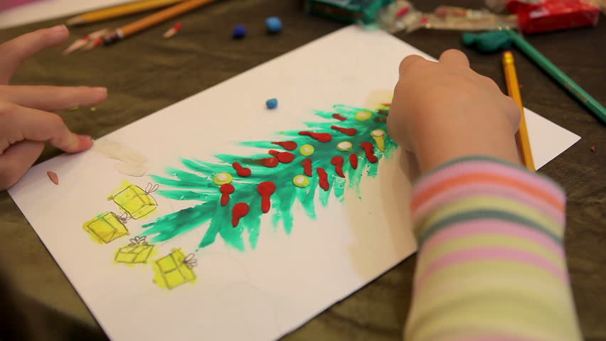 Close up of a childs hand draw christmas fir-tree from plasticine.