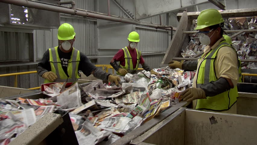 ORLANDO, FL - CIRCA 2009: Workers on assembly line sort through paper waste on conveyor belt circa 2009 in Orlando.
