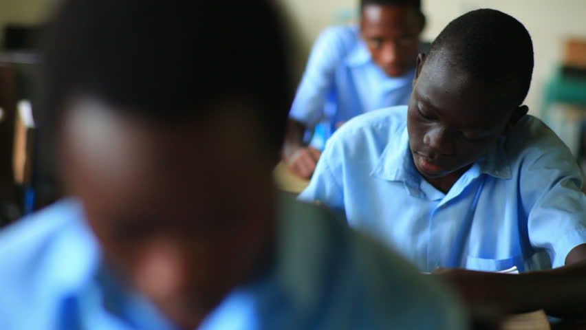 KENYA, AFRICA - CIRCA 2011: Shot of a school boy reading his book in class, then looking up, in Kenya, Africa.