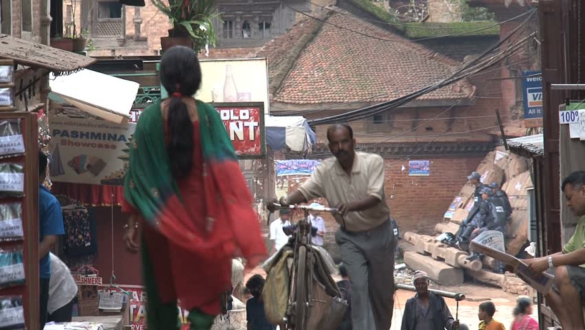 NEPAL - CIRCA MAY, 2011: A man pushes a bike through a pedestrianised street in Nepal.