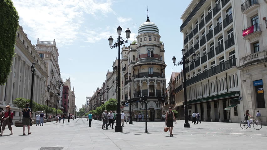 SEVILLE SPAIN MAY 17 2011: Spectators walk historic city center and flatiron building in Seville Spain. Tourism money important to struggling economy. Destination international tourists. Timelapse.