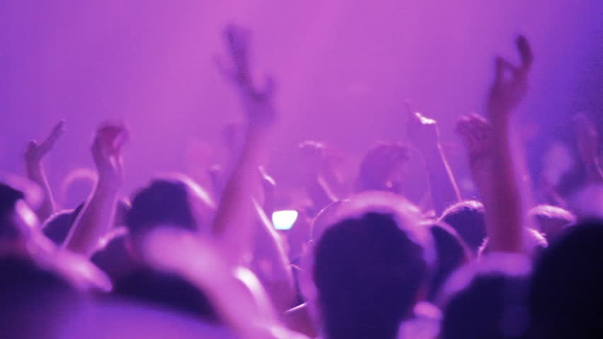 Lot of people clapping at rave party, view from behind, hands and heads, displays of photo cameras