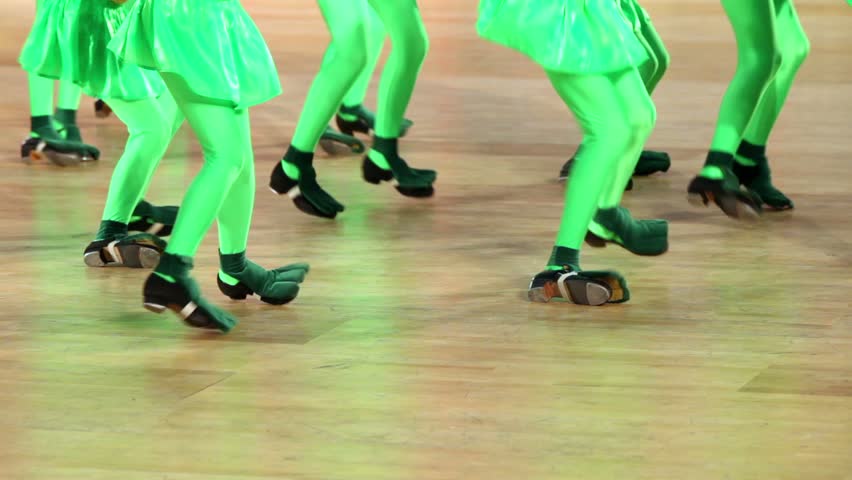 Several girls in shoes with taps and green costume of frog tap dance, only legs are visible