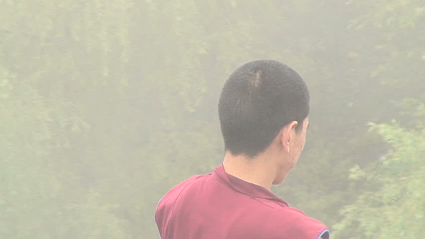 MCLEOD GANJ, INDIA - AUGUST 20, 2006: Buddhist monk looking out over misty landscape