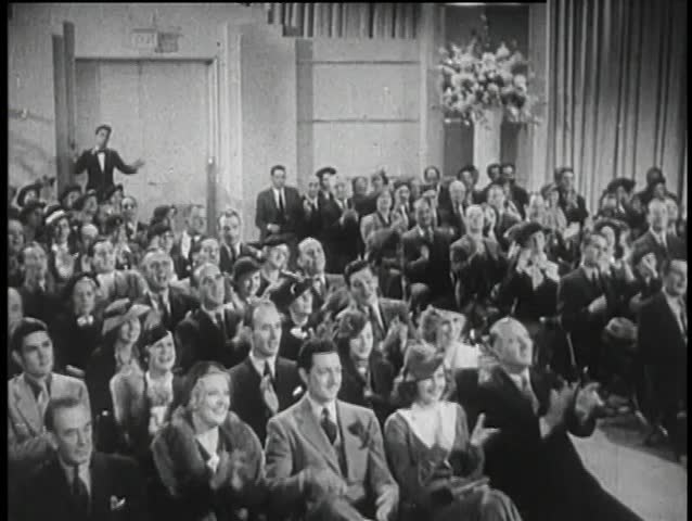 Wide shot of 1930s audience applauding