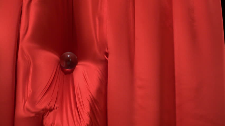 Clear glass ball falling onto velvet cloth