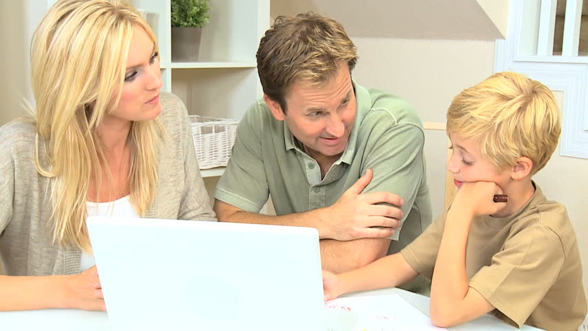 Proud parents watching son using laptop and crayons
