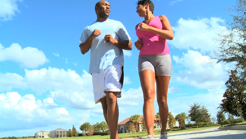 Young ethnic couple keeping to a fitness program together jogging outdoors