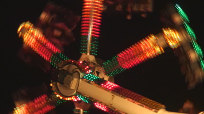Hundreds of colored lights flash on rotating amusement park ride at night