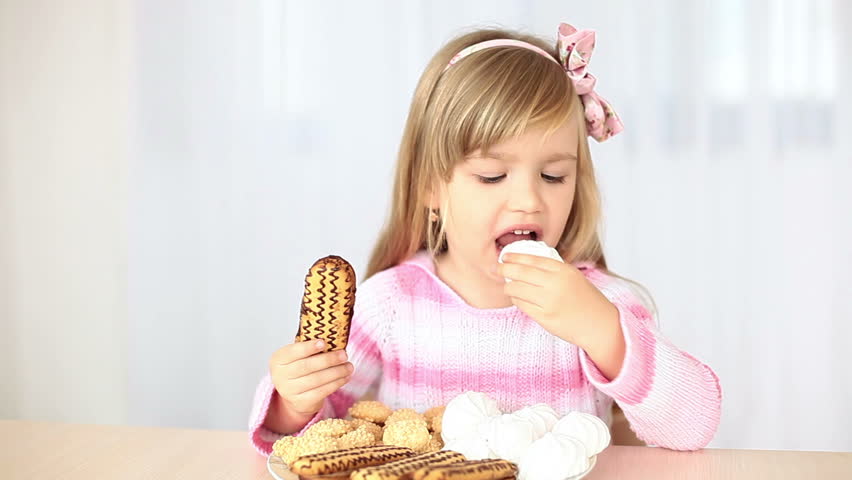 Happy little girl eats candy