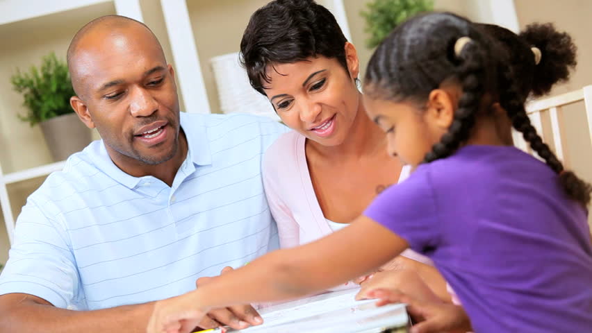 Young african american parents watching their cute young daughters using coloring crayons