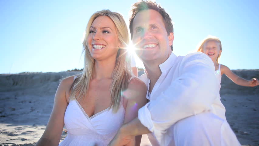 Attractive caucasian parents giving their children a piggyback on the beach