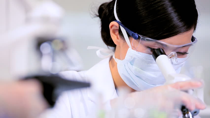 Asian chinese lab assistant examiing medical specimens under a microscope
