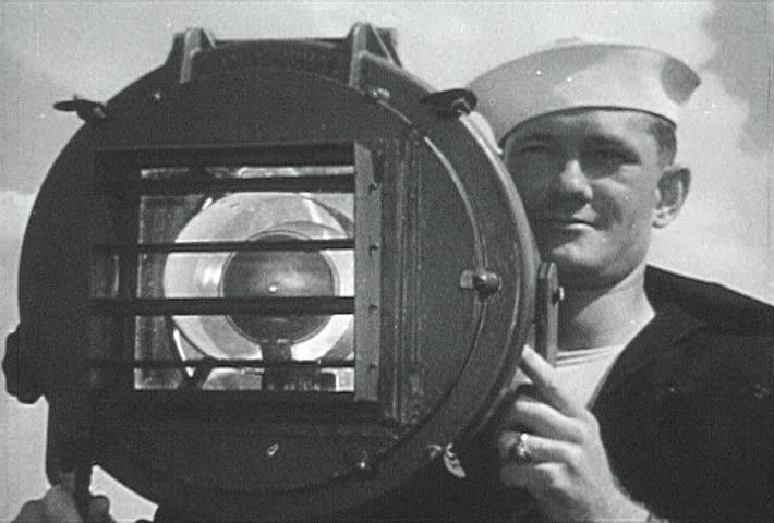ATLANTIC OCEAN - CIRCA 1942-1944: World War II, Ship Crew Communicating with Navy Signal Lamp, publisher National Broadcasting Service (U.S.)