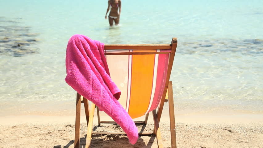 female coming out from sea drying out and sitting on deckchair