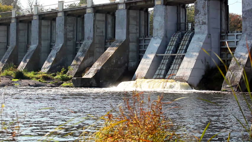Dam with current water and red bushes in the foreground