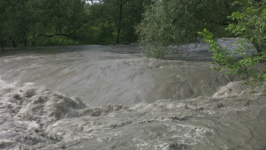 A wide angle view showing a fast moving and swollen river after a flash flood.