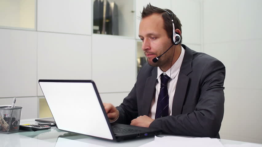 Young helpdesk consultant talking on headset in modern office