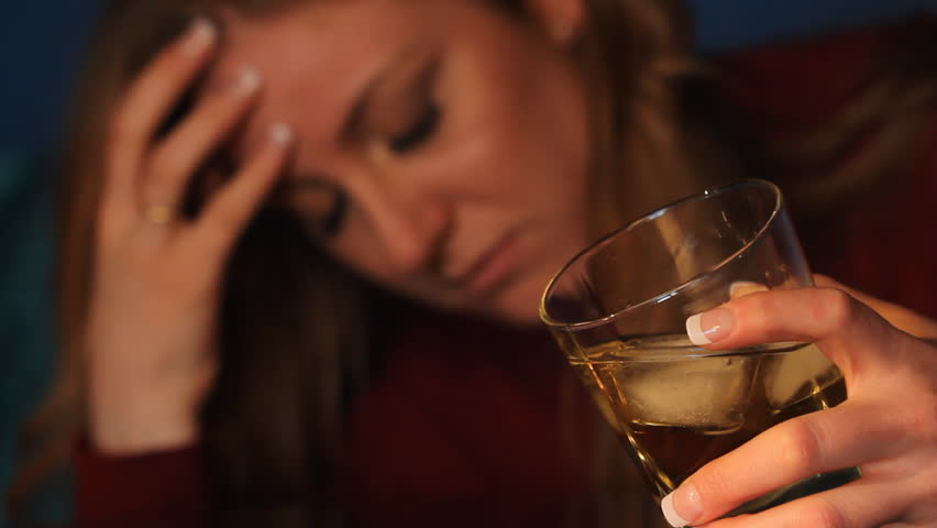 Woman drinking alcohol. Glass in sharp focus. Shallow DOF.