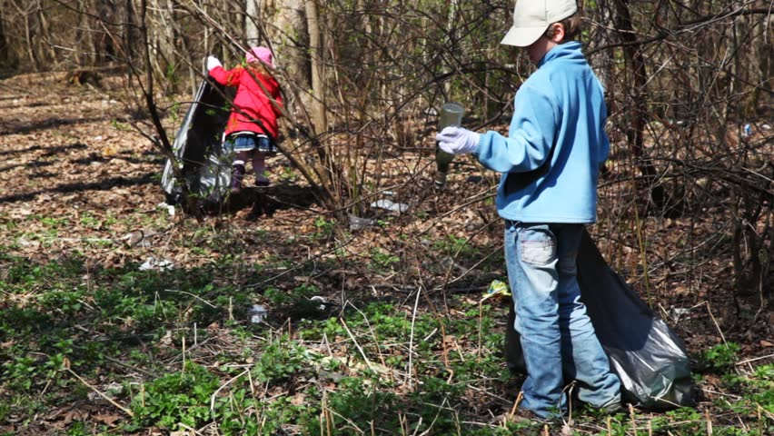 little boy and girl with black bags cleaned nature, collect trash in park at spring