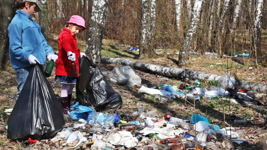 little boy and girl with black bags collect lot of garbage in park at spring