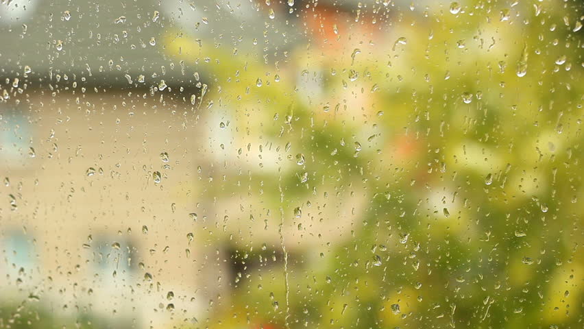 Rainy day in fall. The rain drops on household windows. Focus on rain drops running down the window. 