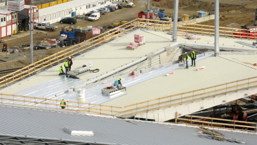 Workers lay an insulating cover on roof, time lapse