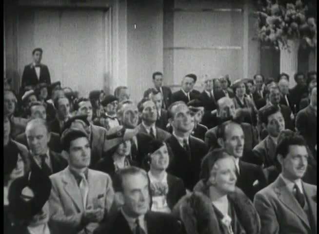 Wide shot of 1930s audience applauding