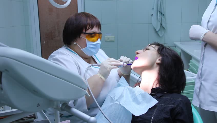 Dentist inspecting female patient's mouth