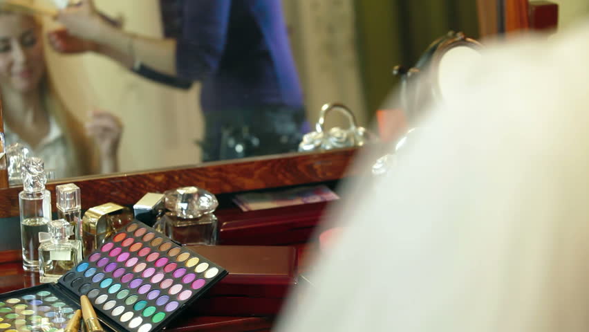 Bridal hairdresser making hairstyle in front of a mirror at home. 