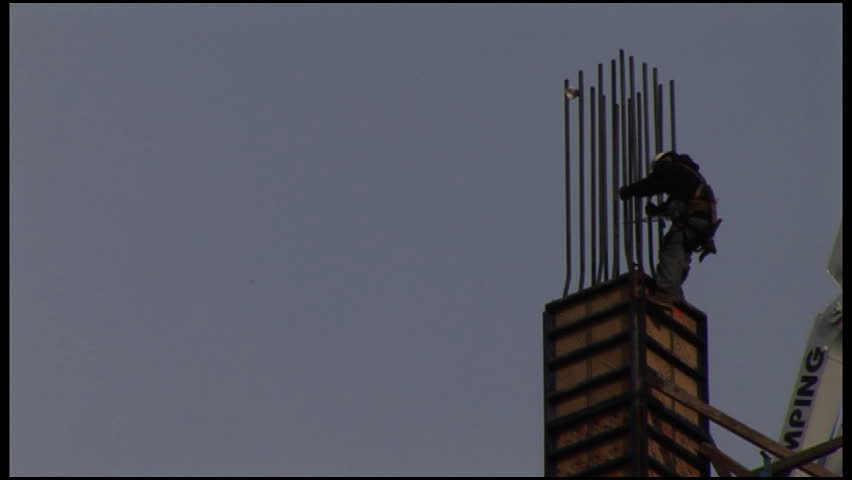 Construction worker climbing to work on building under construction SD