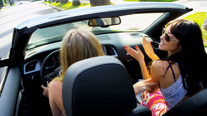 Laughing girls listening to the radio in a luxury convertible