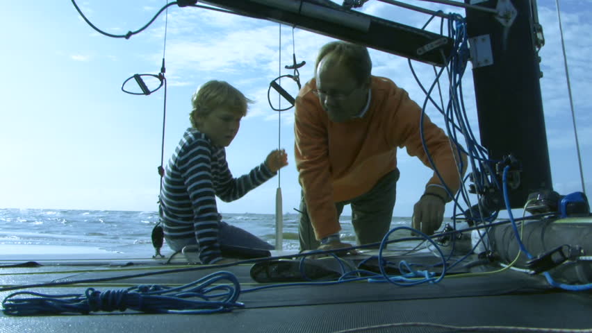 MEDIUM SHOT, Father giving son instructions on sailboat