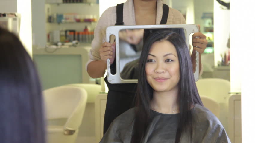 MEDIUM SHOT, Hairdresser showing to customer hair cut