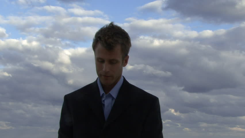 Cu of a male opening an umbrella on a beach and checking if it is raining
