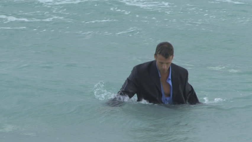 Male walking out of the ocean in suit