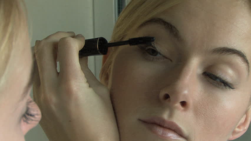 WIDE SHOT ZOOM IN ZOOM OUT OF YOUNG WOMAN APPLYING MASCARA