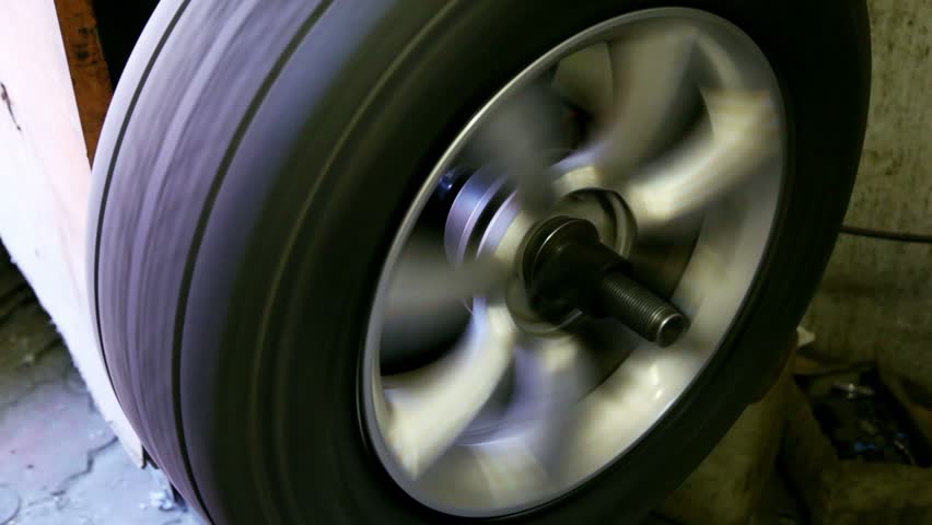 Man adjust balance of car wheel on special machine, closeup view