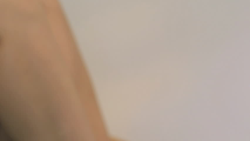 CLOSE UP PAN OF A YOUNG WOMAN APPLYING MOISTURIZER ON WHITE BACKGROUND