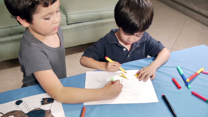 Young Boys Coloring. Two brothers of Hispanic origin; 6 and 4 years old coloring an insect figure drawing with felt pens.