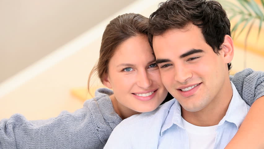 Couple in love are smiling at the camera while sitting down