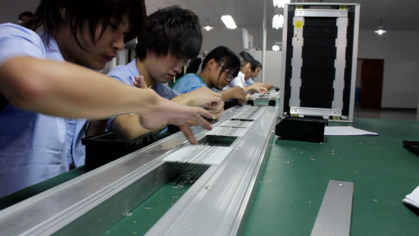 KUNSHAN, CHINA - 22 September 2011: A Group of workers manually assemble Electronic parts and Components on a Printed Circuit Board at a Factory. Kunshan, China - 22 September 2011