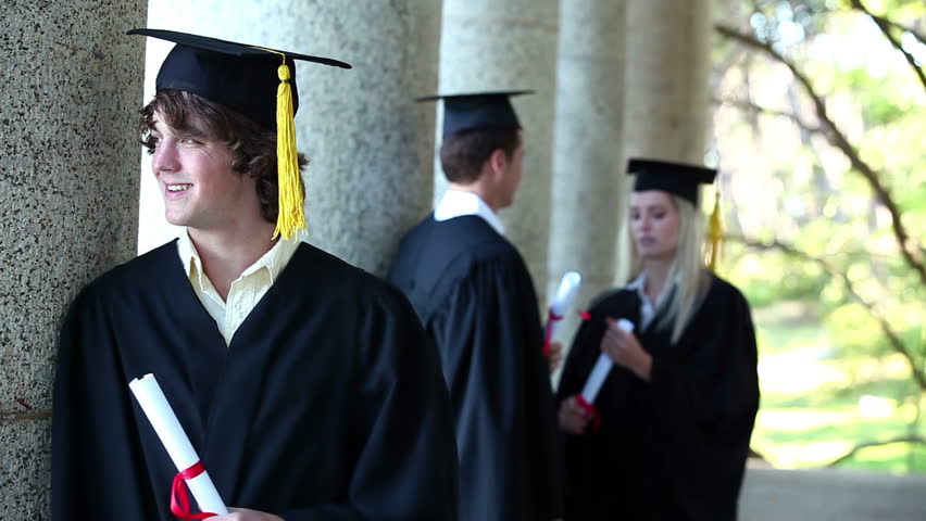 Portrait of a male graduate in foreground leaning against column