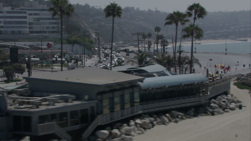 aerial flying shot moving along bends in the rocky coastline, parallel to highway and businesses in the background circa 2009