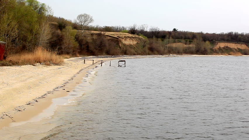 Reservoir with the steep coast in the distance and the wood ashore