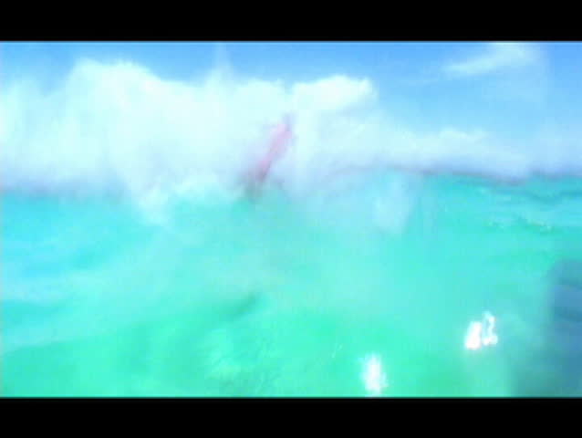 Shot in beautiful tropical waters this hot kiteboarding chick flys by the camera with a big smile. Shot from the water's point of view.